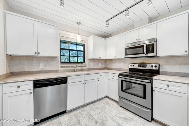 a kitchen with granite countertop white cabinets and stainless steel appliances