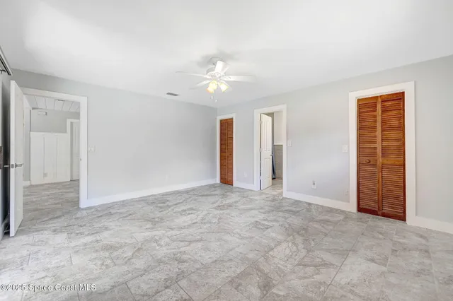 an empty room with closet and a ceiling fan