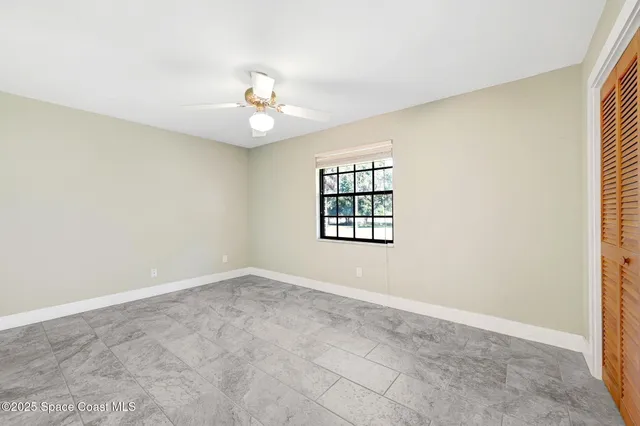 an empty room with windows and ceiling fan