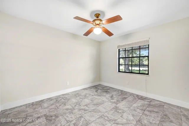 an empty room with window and ceiling fan