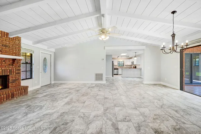 a view of a livingroom with a chandelier fan and kitchen view