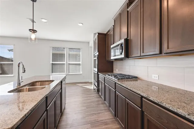 a kitchen with stainless steel appliances granite countertop a sink stove and cabinets