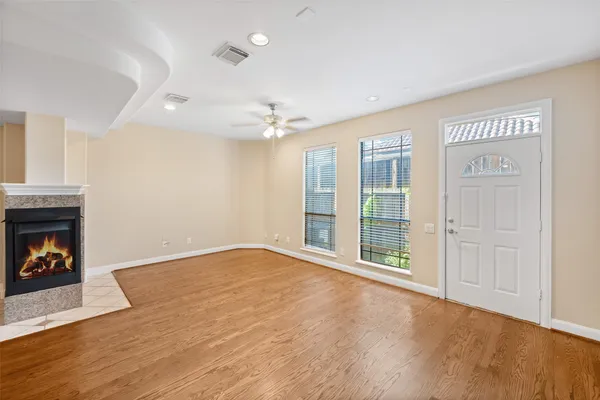 an empty room with wooden floor fireplace and windows