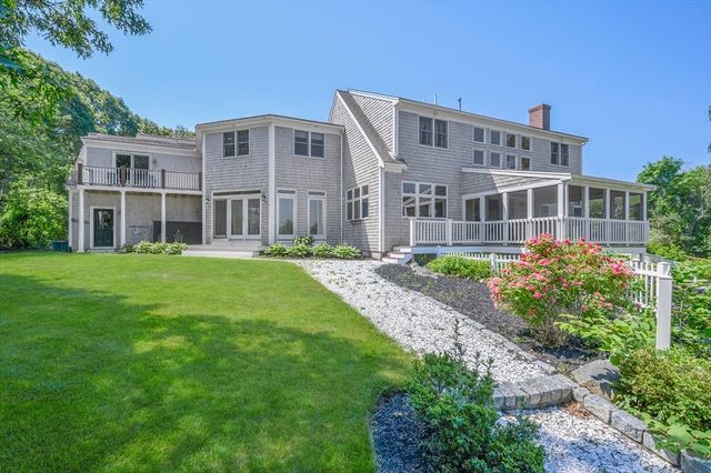 a front view of a building with garden and trees