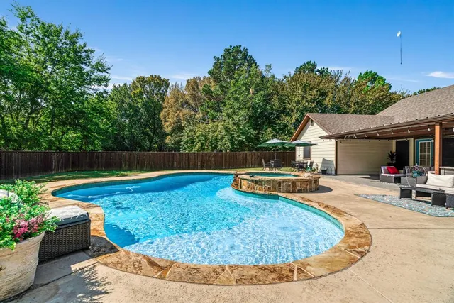 a view of a backyard with couches potted plants and swimming pool