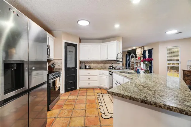 a kitchen with stainless steel appliances granite countertop a refrigerator and a stove top oven