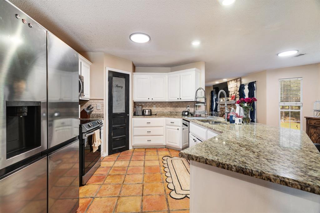 258 County Road Powderly, TX 75473 - Photo 10 of 24 a kitchen with stainless steel appliances granite countertop a refrigerator and a stove top oven