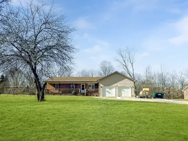 a view of house with a big yard and large trees