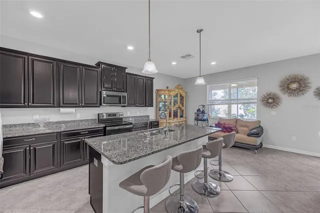 a kitchen with stainless steel appliances granite countertop a stove a sink a oven a dining table and chairs