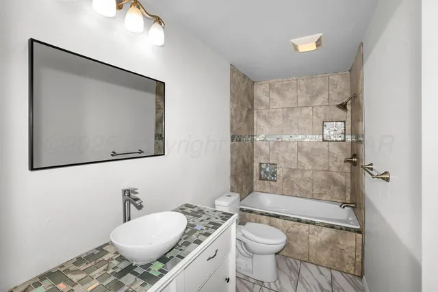 a bathroom with a granite countertop sink toilet a mirror and shower
