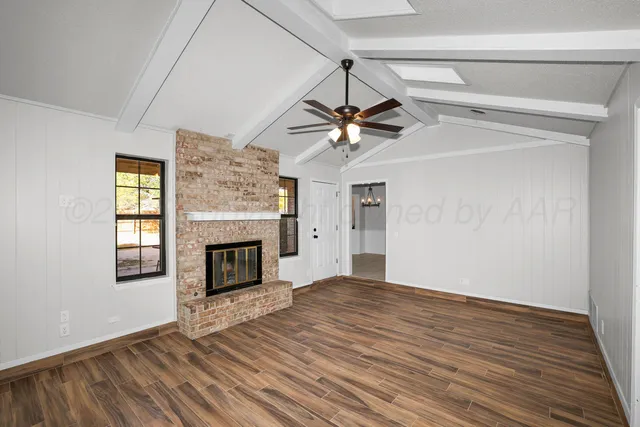 a view of a livingroom with a fireplace a ceiling fan and brick wall clock