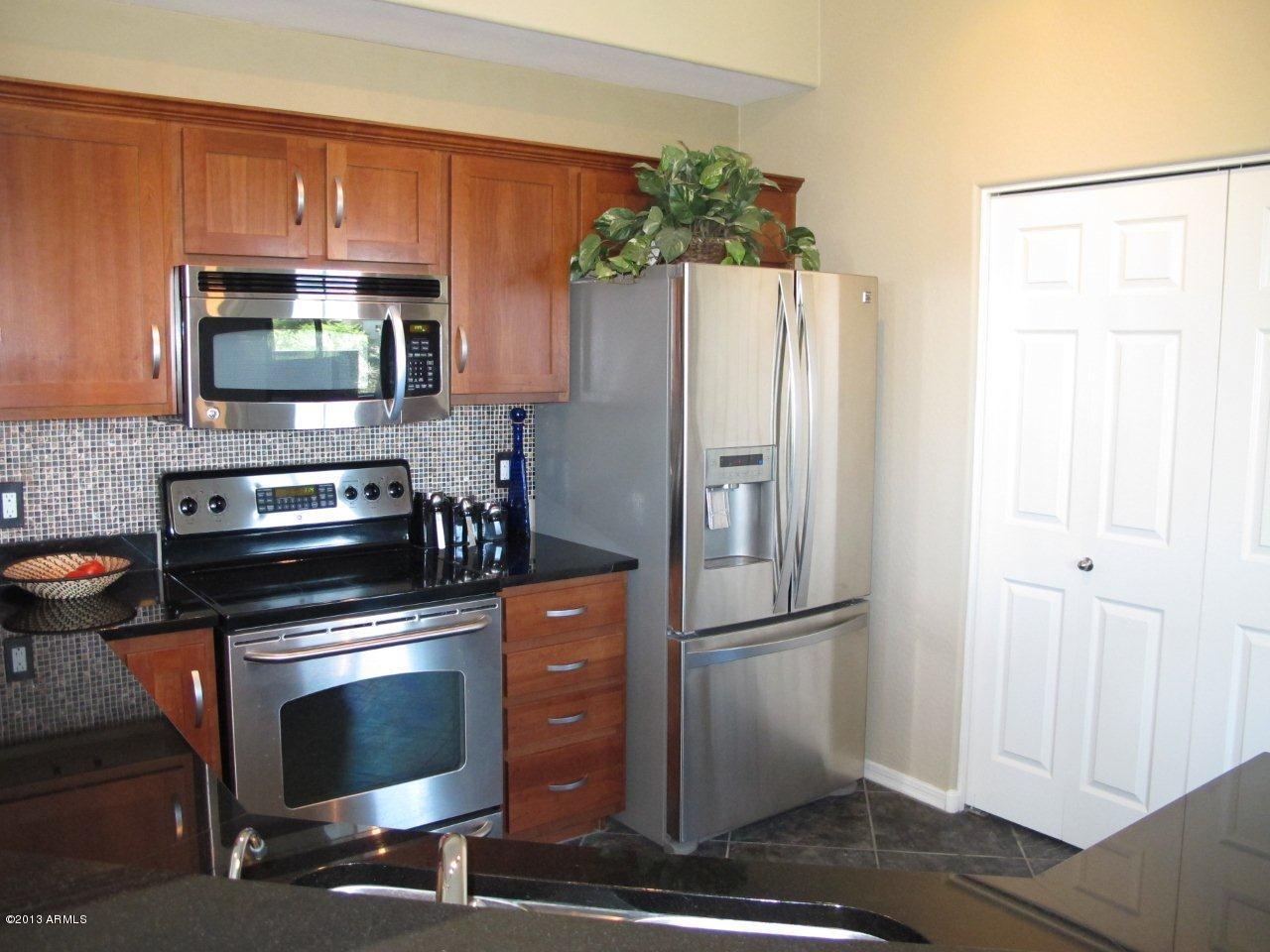 3330 South Gilbert Road, Unit 2014 Chandler, AZ 85286 - Photo 8 of 30 a kitchen with granite countertop a refrigerator stove and microwave