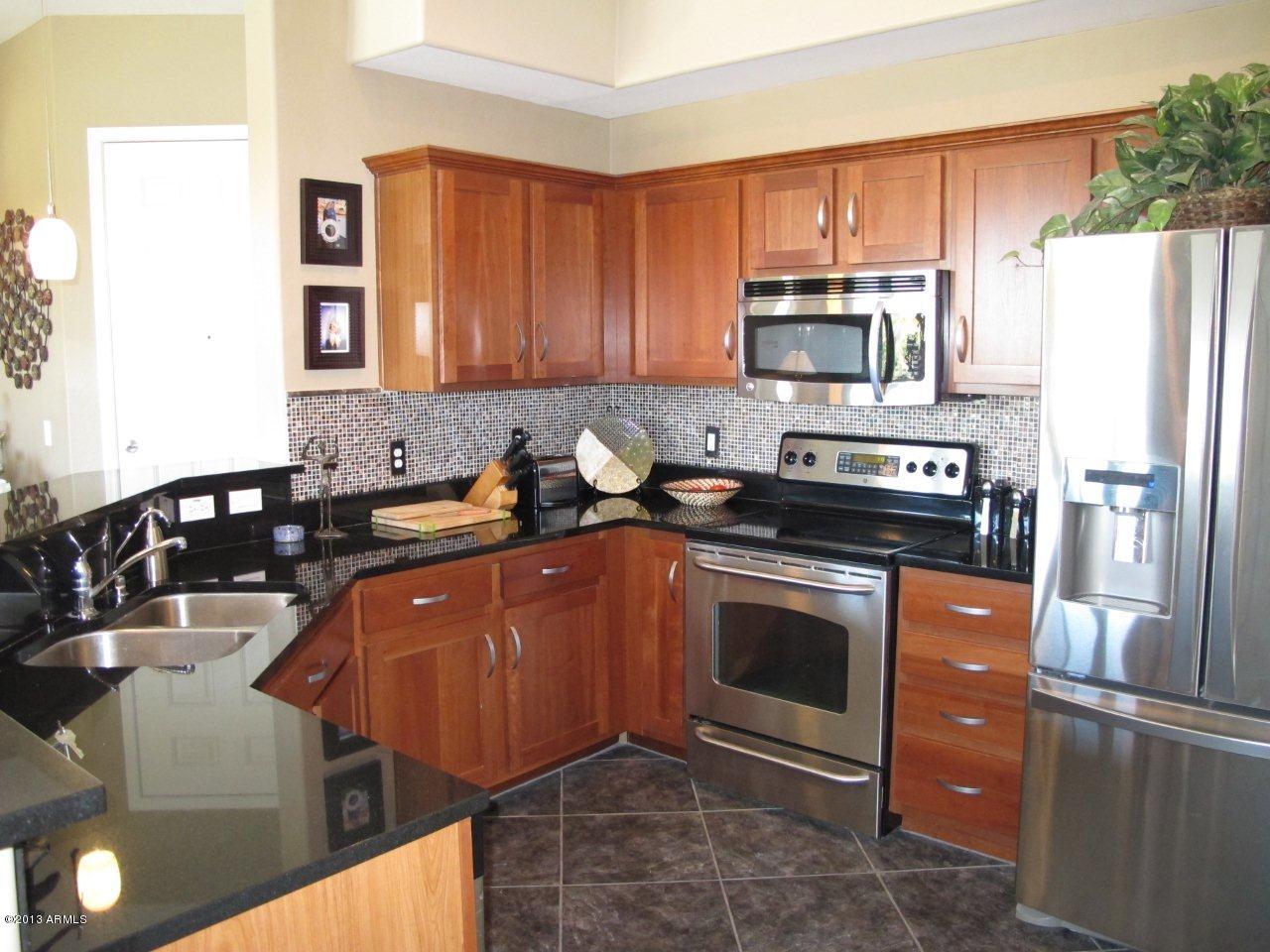 3330 South Gilbert Road, Unit 2014 Chandler, AZ 85286 - Photo 9 of 30 a kitchen with stainless steel appliances granite countertop a stove a sink dishwasher and a refrigerator with wooden cabinets