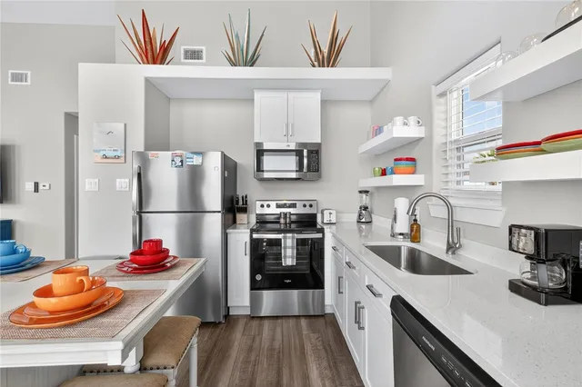 a kitchen with stainless steel appliances granite countertop a sink dishwasher and a refrigerator