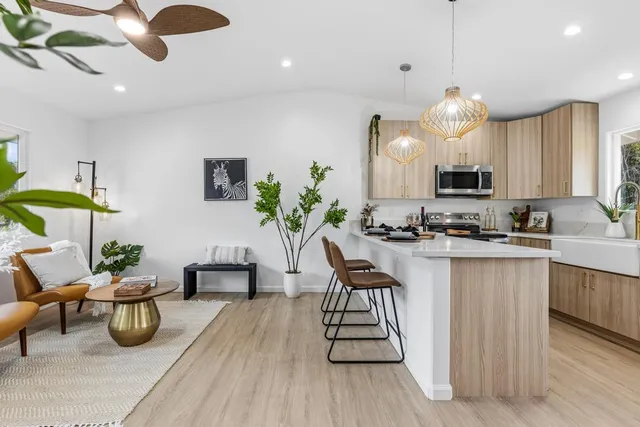 a kitchen with stainless steel appliances kitchen island granite countertop a sink a stove a dining table and chairs with wooden floor