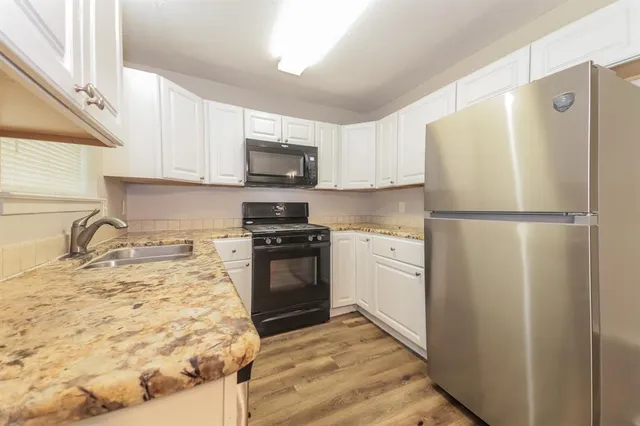 a kitchen with granite countertop a refrigerator stove and sink