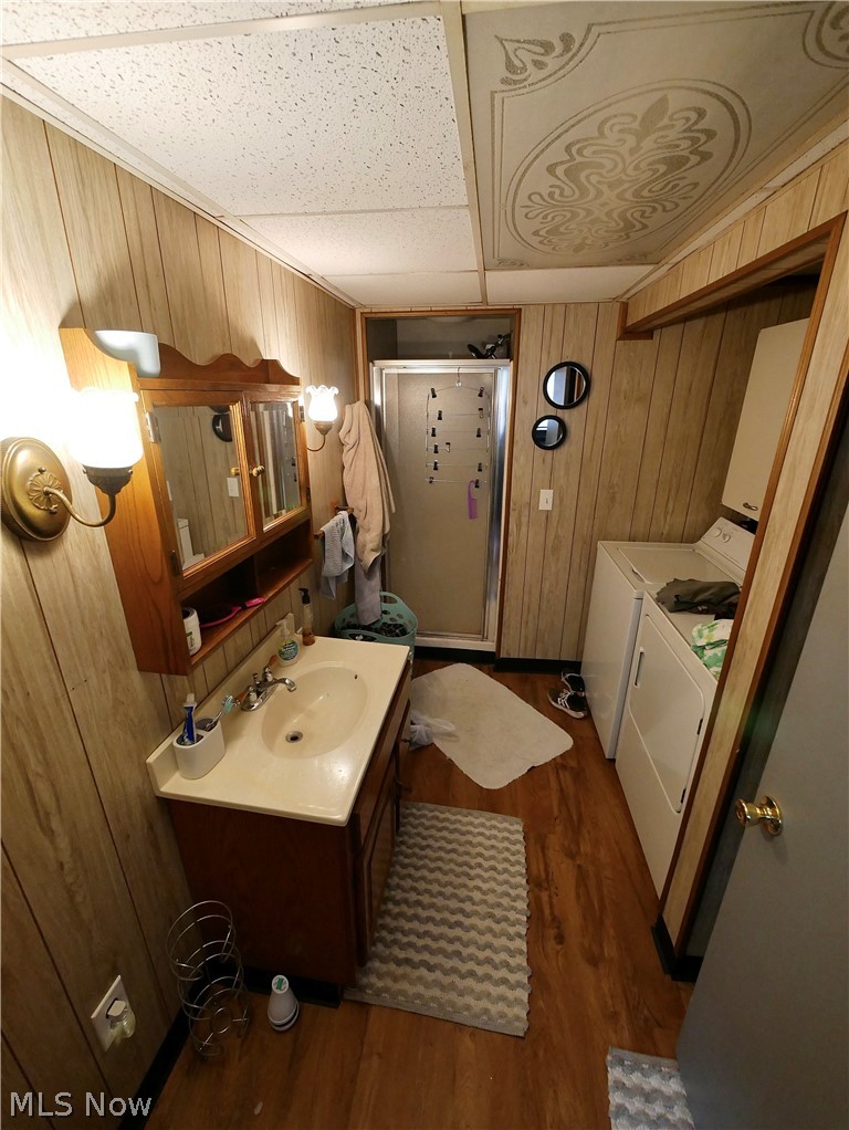 75450 Fair Road Freeport, OH 43973 - Photo 39 of 45 Bathroom featuring independent washer and dryer, a paneled ceiling, hardwood / wood-style floors, wooden walls, and vanity