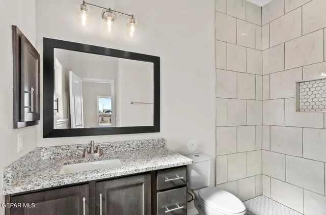 a bathroom with a granite countertop sink toilet and mirror