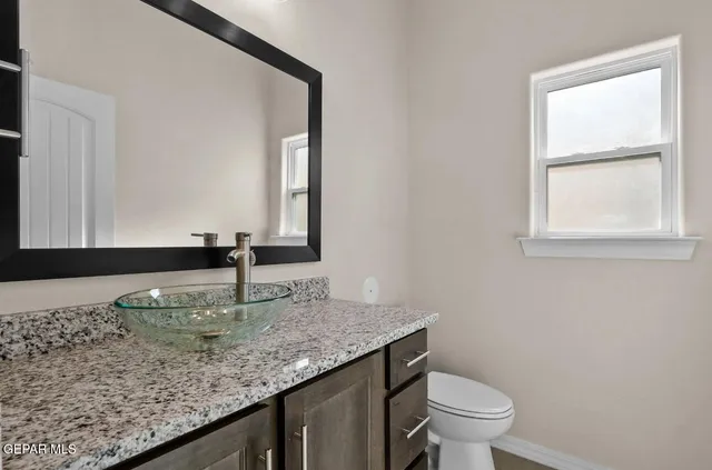 a bathroom with a granite countertop sink and a toilet