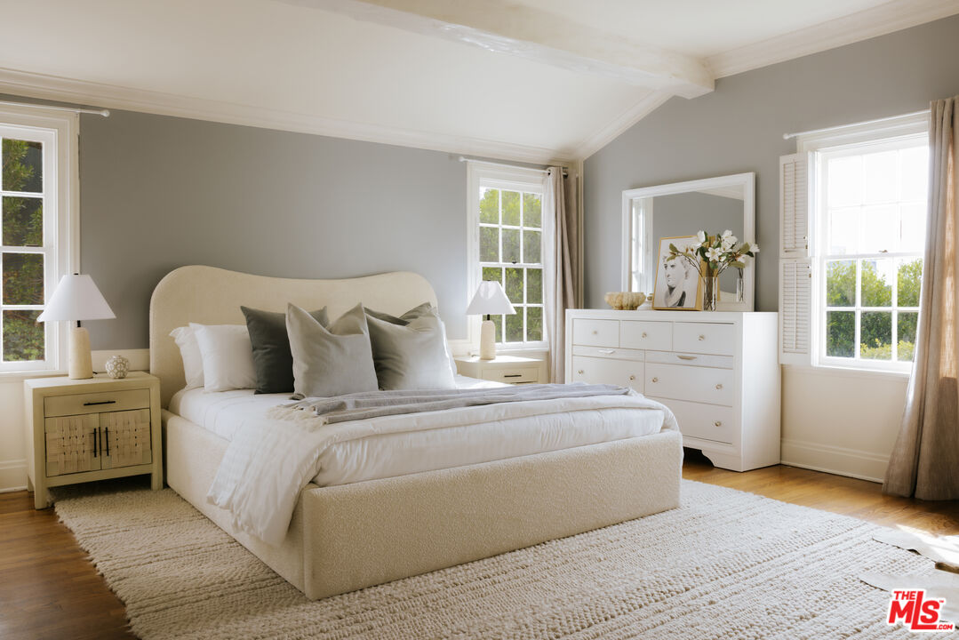 11630 Bellagio Road Los Angeles, CA 90049 - Photo 8 of 18 a spacious bedroom with a bed and wooden floor