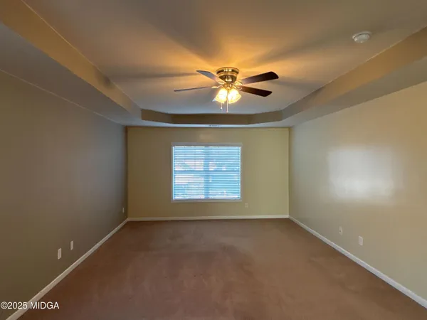 en empty room with windows and chandelier fan