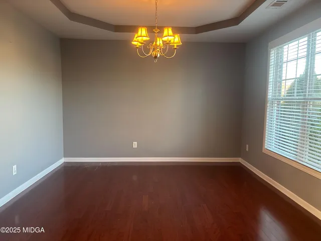 an empty room with wooden floor and windows in walls
