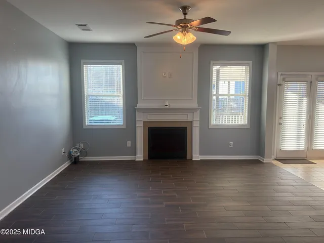an empty room with wooden floor fireplace and windows