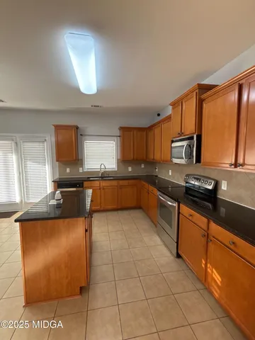 a large kitchen with granite countertop a stove a sink and a microwave