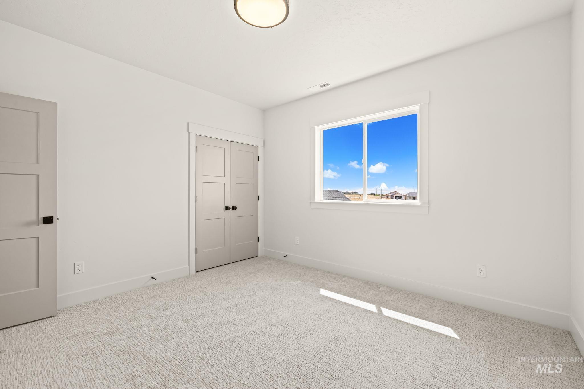 345 South Strut Way Boise, ID 83716 - Photo 42 of 50 White walls, light carpet flooring, contemporary ceiling light fixture, three-panel interior doors, and a double-pane window
