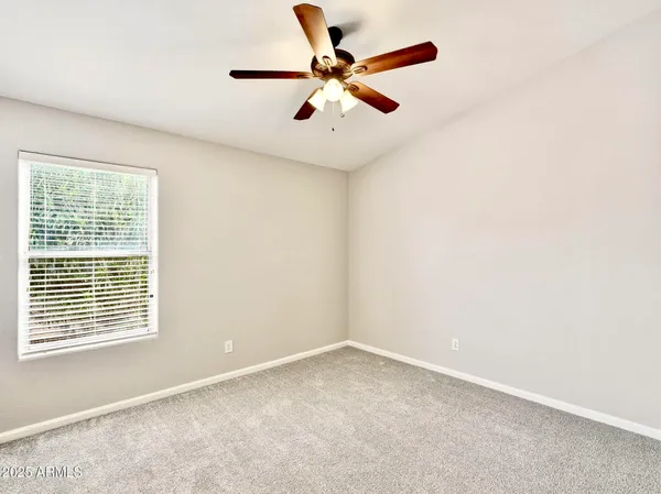 an empty room with a window and a ceiling fan
