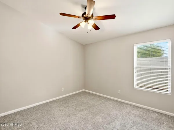an empty room with windows and fan