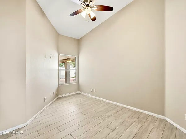 an empty room with a window and a chandelier fan