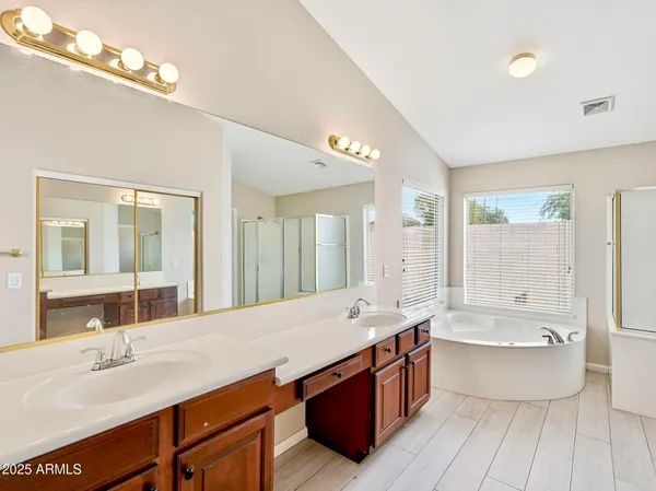 a spacious bathroom with a tub double sink and mirror