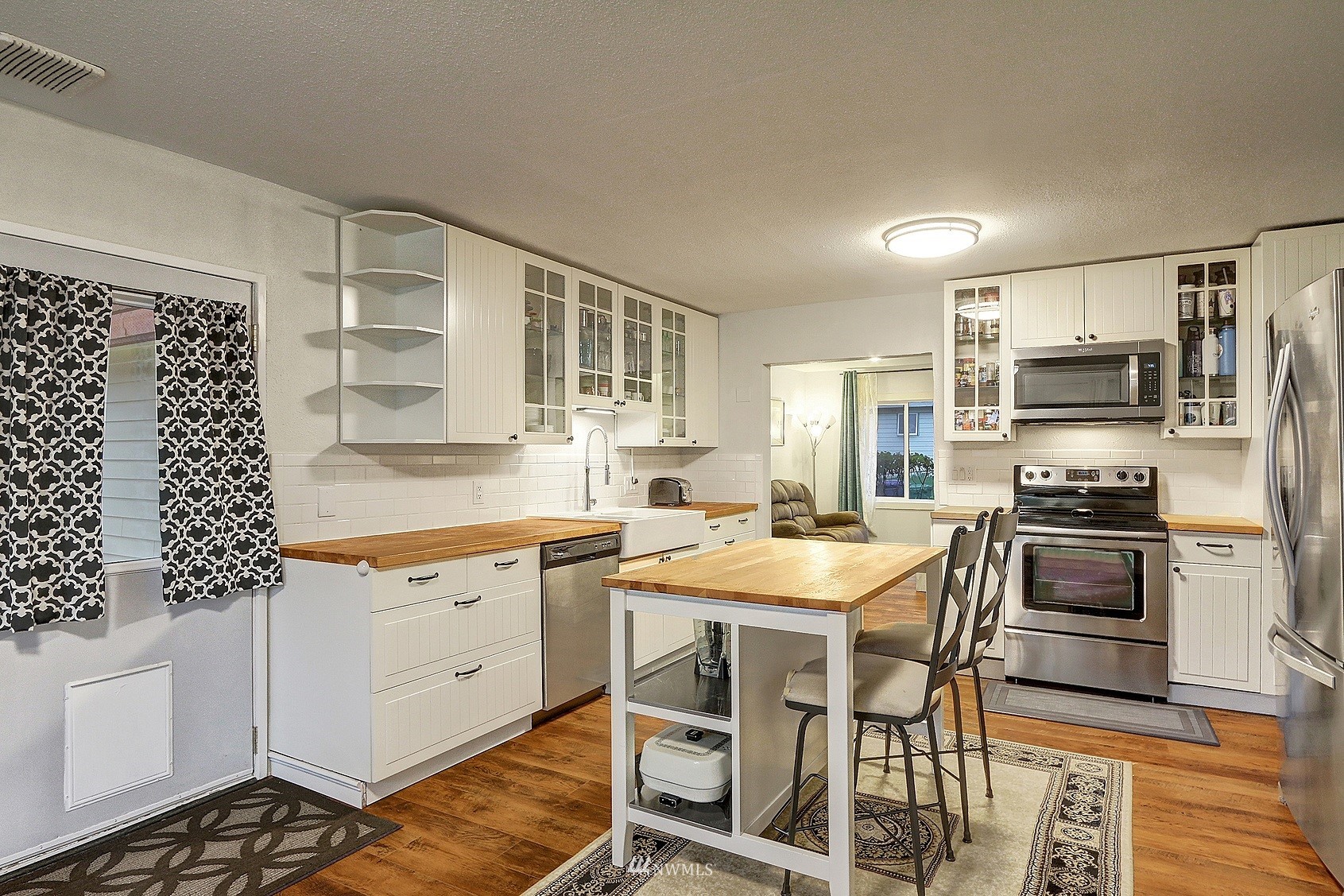 2209 Northeast 8th Street Renton, WA 98056 - Photo 2 of 24 a kitchen with stainless steel appliances kitchen island granite countertop a stove top oven a sink a dining table and chairs with wooden floor