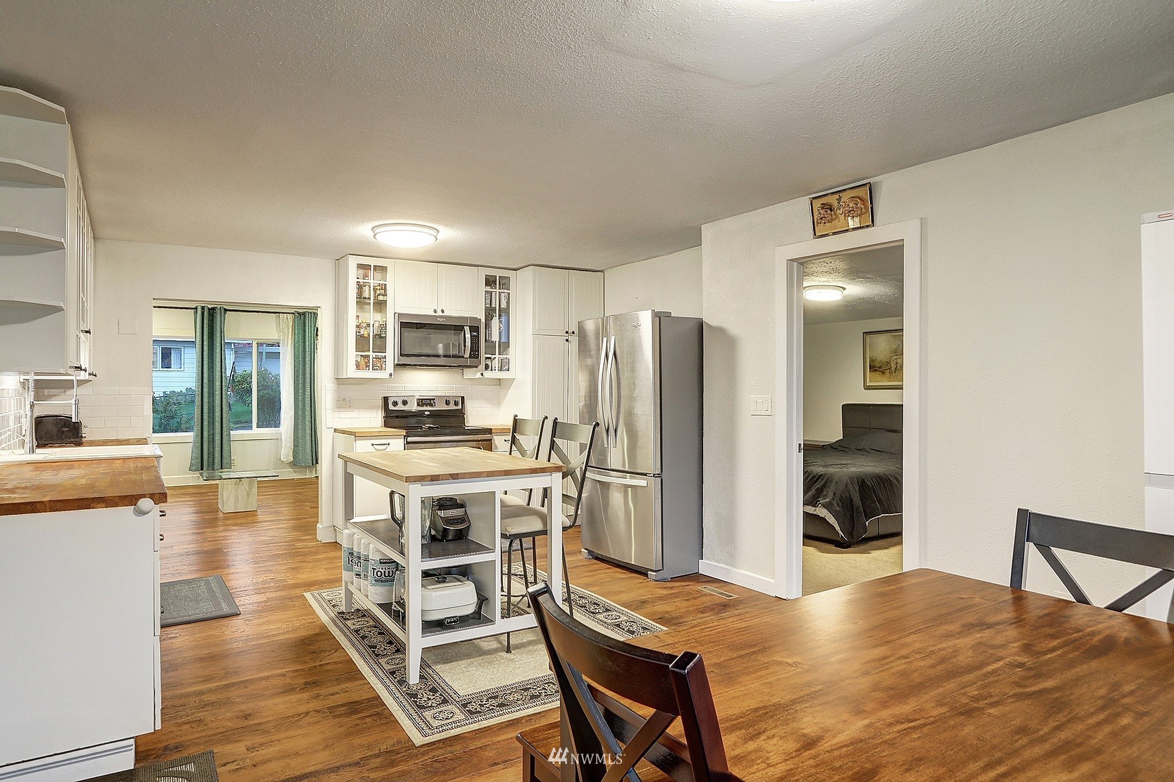2209 Northeast 8th Street Renton, WA 98056 - Photo 5 of 24 a kitchen with stainless steel appliances a stove a refrigerator a sink dishwasher and a dining table with wooden floor