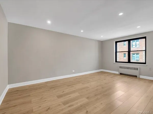 a view of an empty room with a window and wooden floor