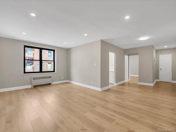 a view of an empty room with a window and wooden floor