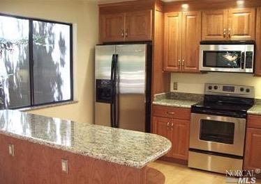 a kitchen with granite countertop a refrigerator stove and microwave