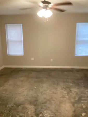 a view of an empty room with window and chandelier fan