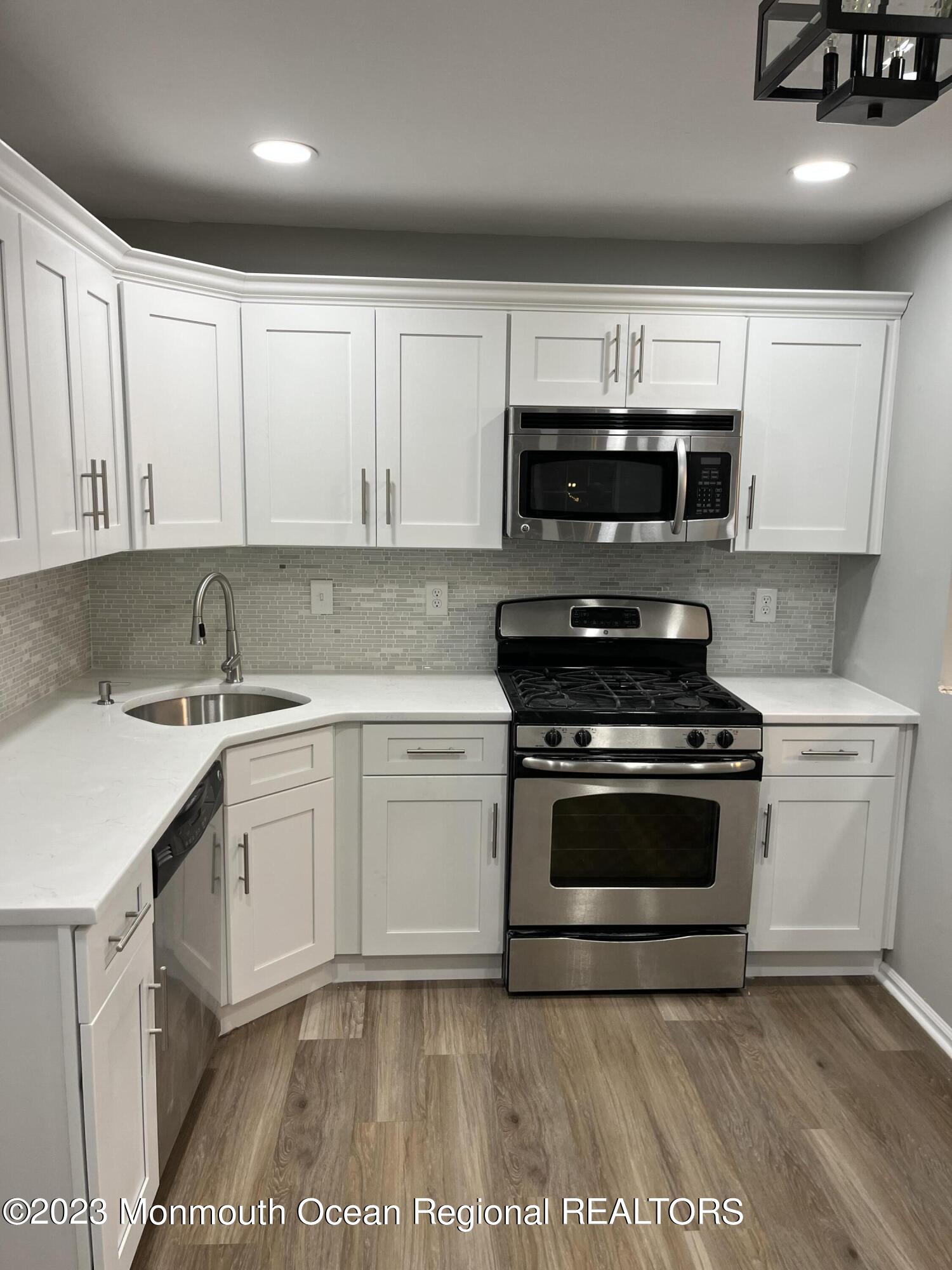a kitchen with stainless steel appliances granite countertop a sink a stove a microwave and cabinets