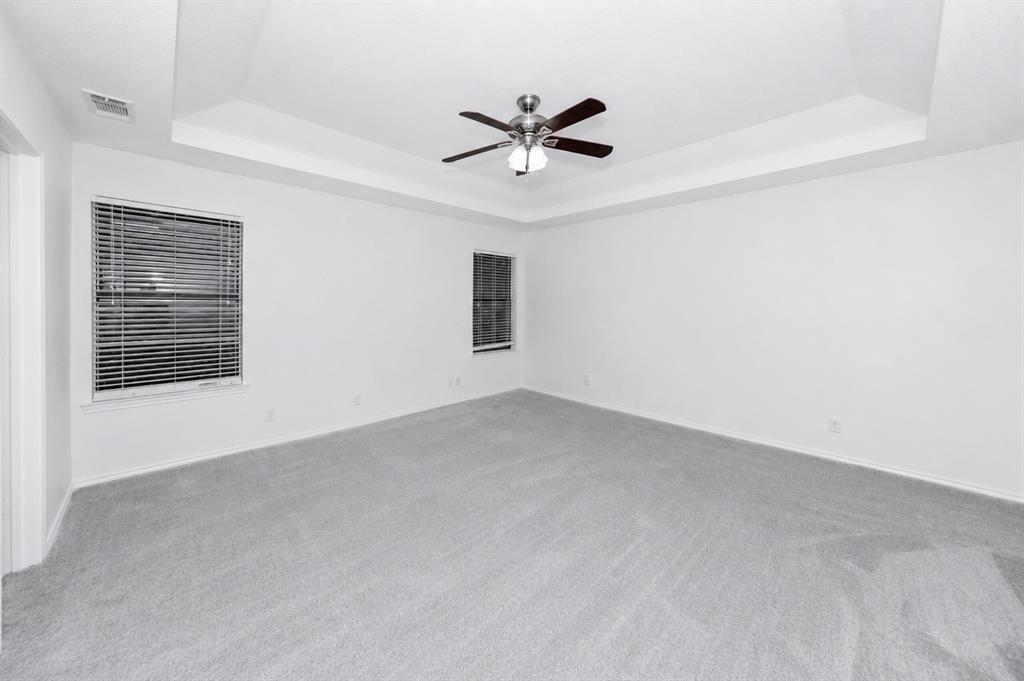 1001 Rosebud Drive Azle, TX 76020 - Photo 26 of 36 Spacious room featuring tray ceiling, ceiling fan with integrated lighting, two windows with blinds, and light-toned carpet flooring
