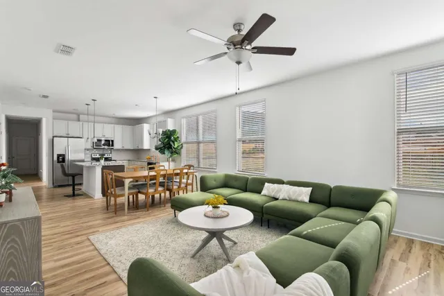 a living room with furniture kitchen view and a large window