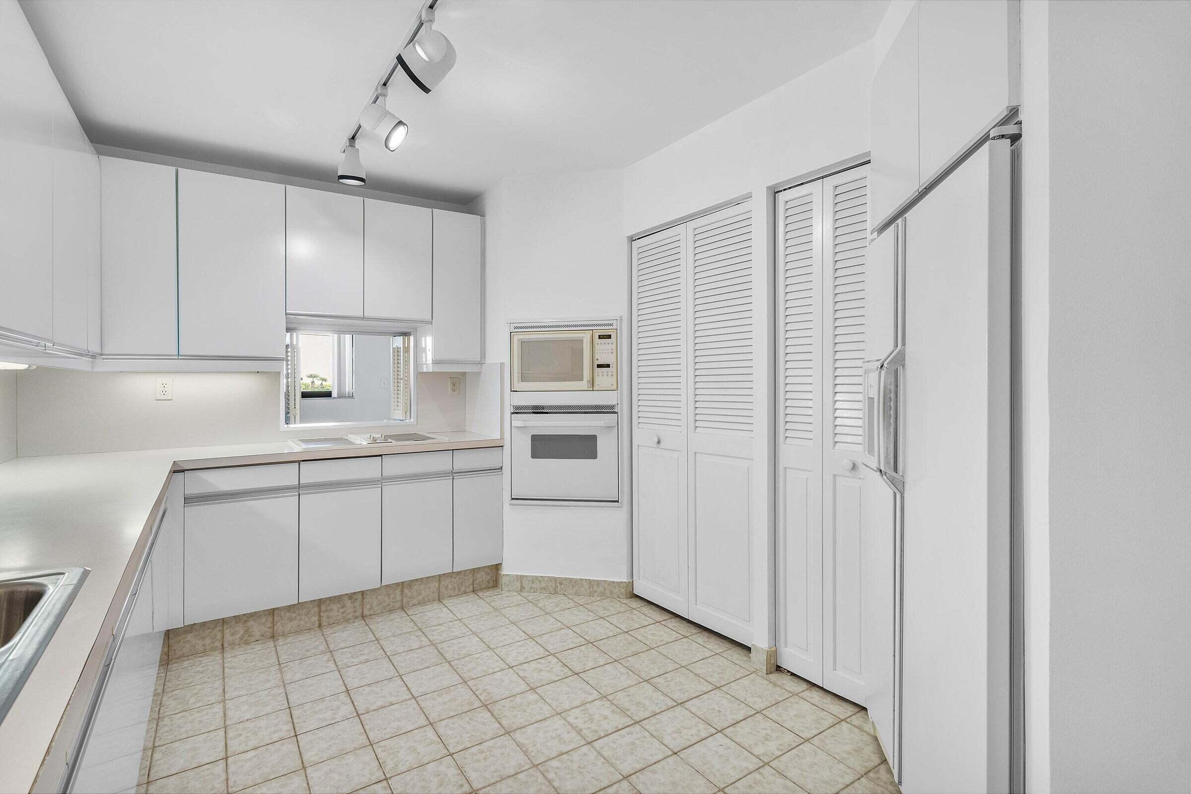 6711 North Ocean Boulevard, Unit 13 Ocean Ridge, FL 33435 - Photo 17 of 50 a kitchen with white cabinets a sink and appliances