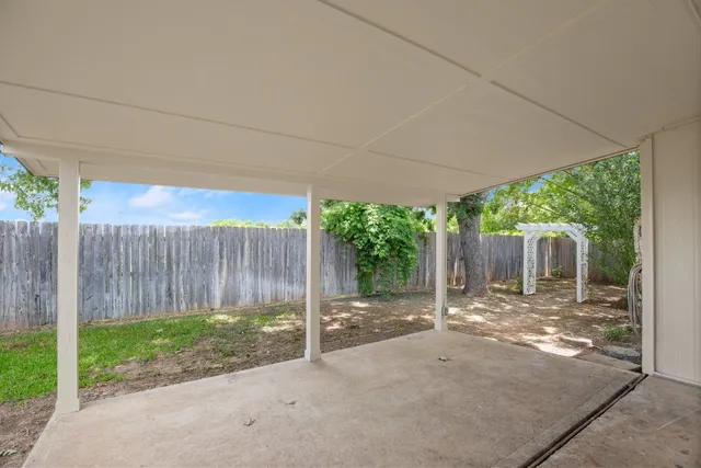 a view of a backyard with wooden fence and large trees