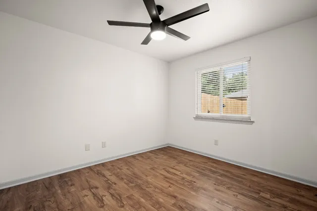 an empty room with a window and a ceiling fan