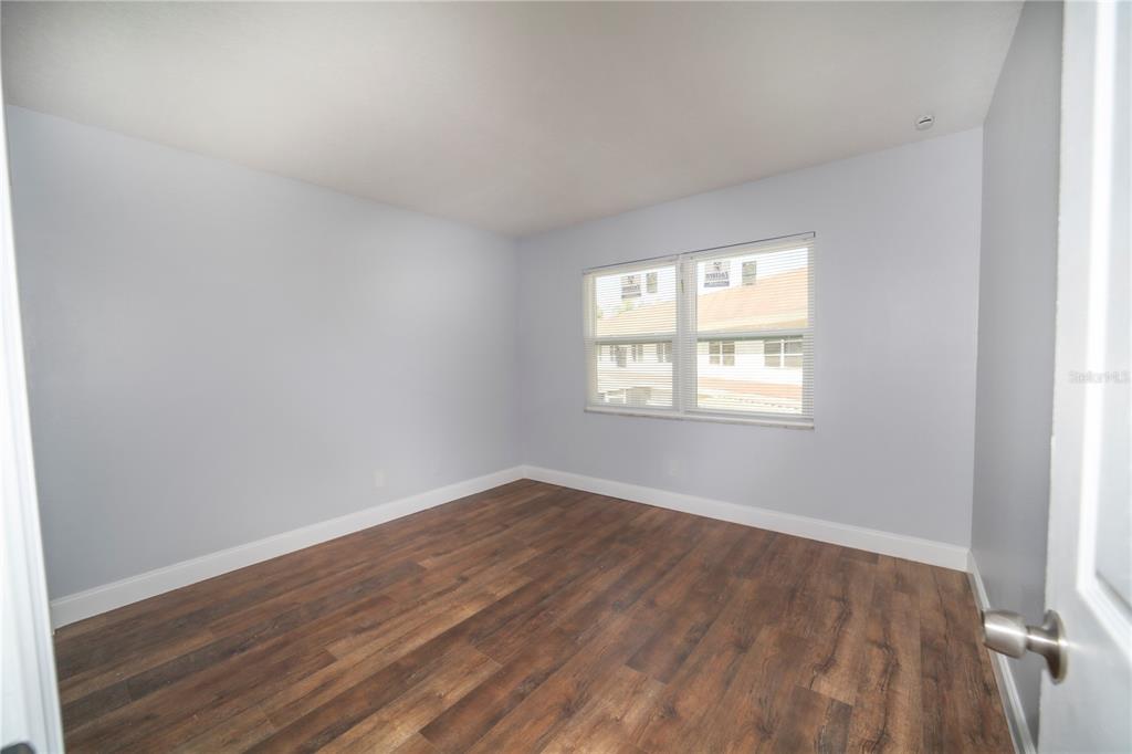 331 Amherst Avenue, Unit 56 Sarasota, FL 34232 - Photo 17 of 19 an empty room with wooden floor and windows
