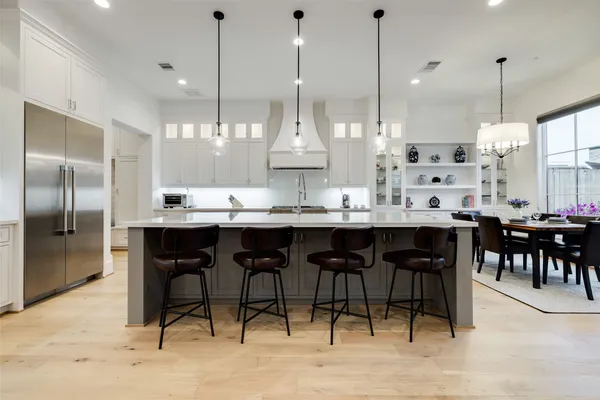 a kitchen with stainless steel appliances kitchen island granite countertop a table chairs sink and cabinets