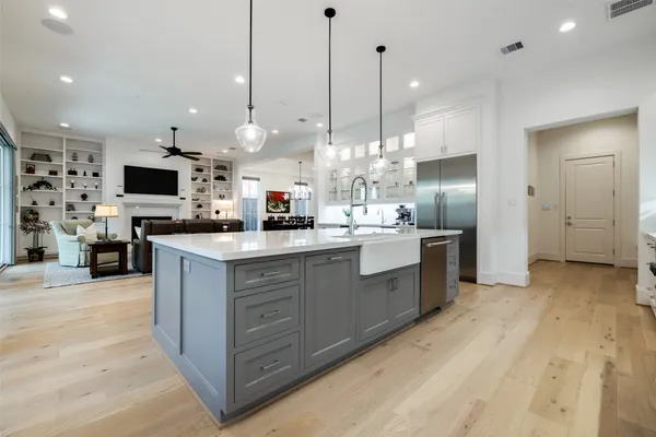a kitchen with stainless steel appliances kitchen island granite countertop a stove a sink a refrigerator and a wooden floor