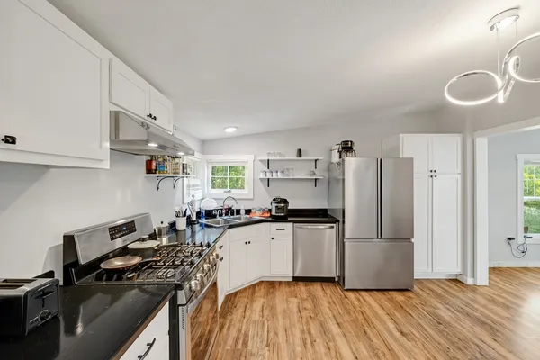 a kitchen with granite countertop a refrigerator stove and sink