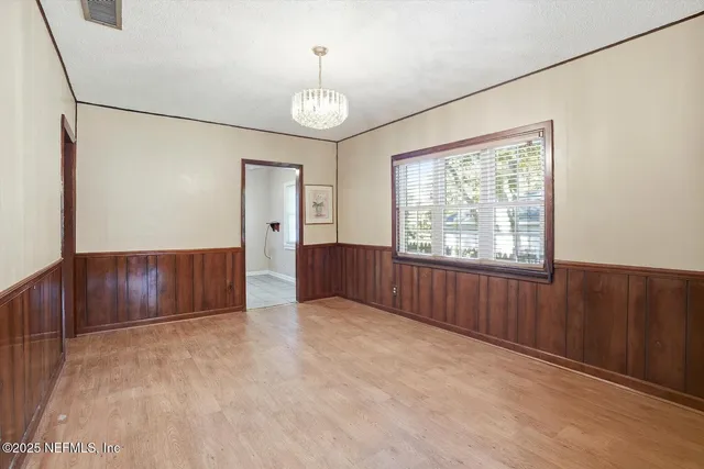 an empty room with chandelier fan and windows